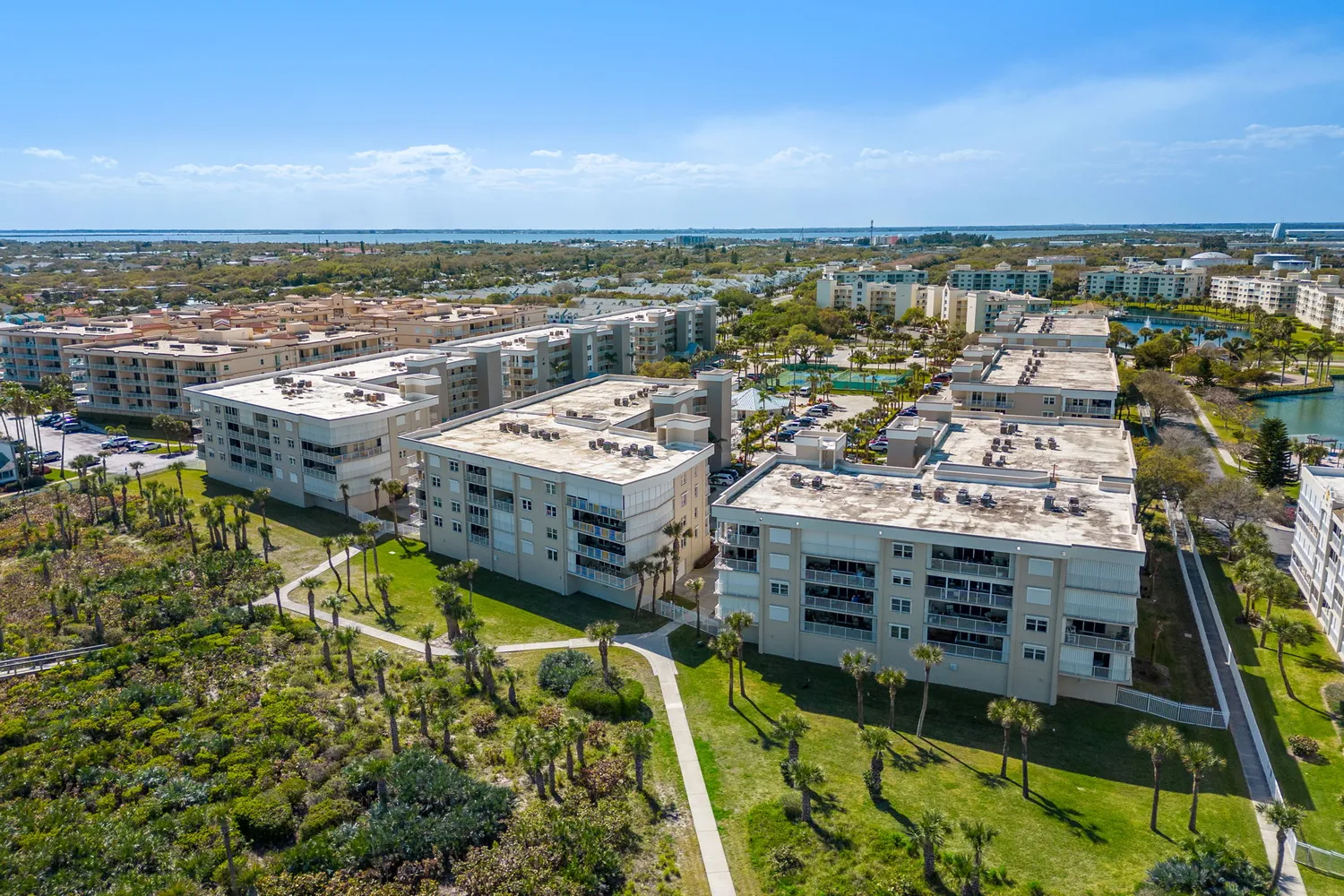 a front view of a building with garden and parking