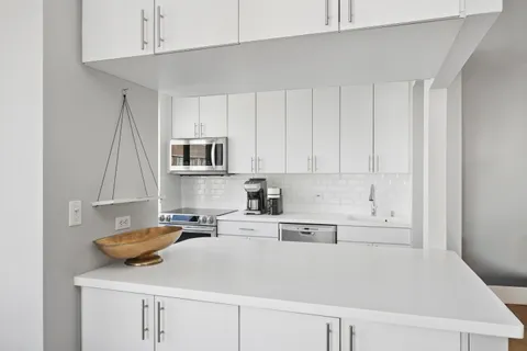 a kitchen with stainless steel appliances granite countertop a sink a stove and white cabinets