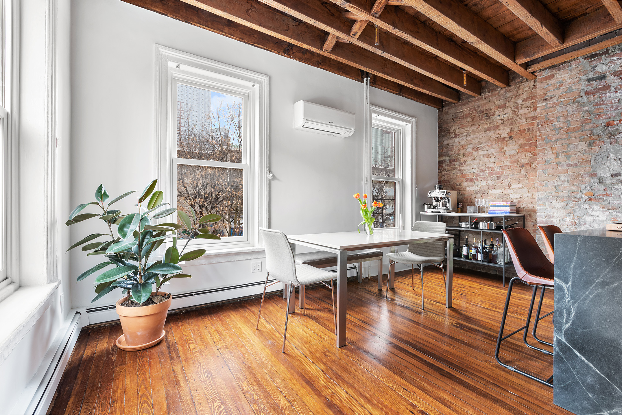 a dining room with furniture potted plants and wooden floor