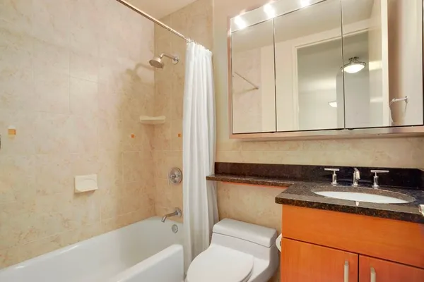 a bathroom with a granite countertop sink mirror toilet and bathtub