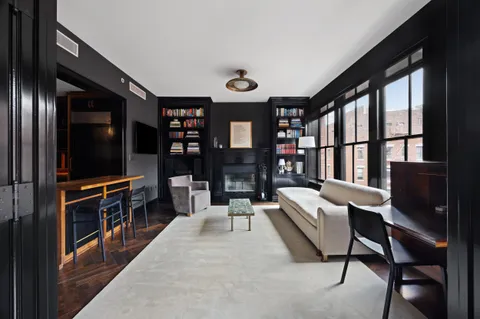 a living room with furniture a flat screen tv and a refrigerator