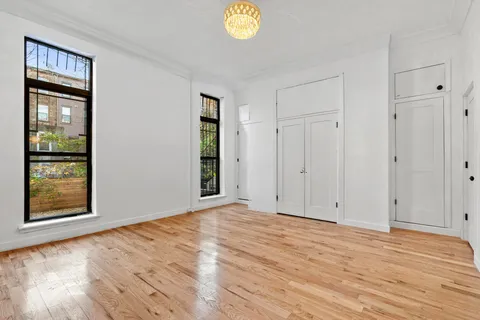 a view of an empty room with window and wooden floor