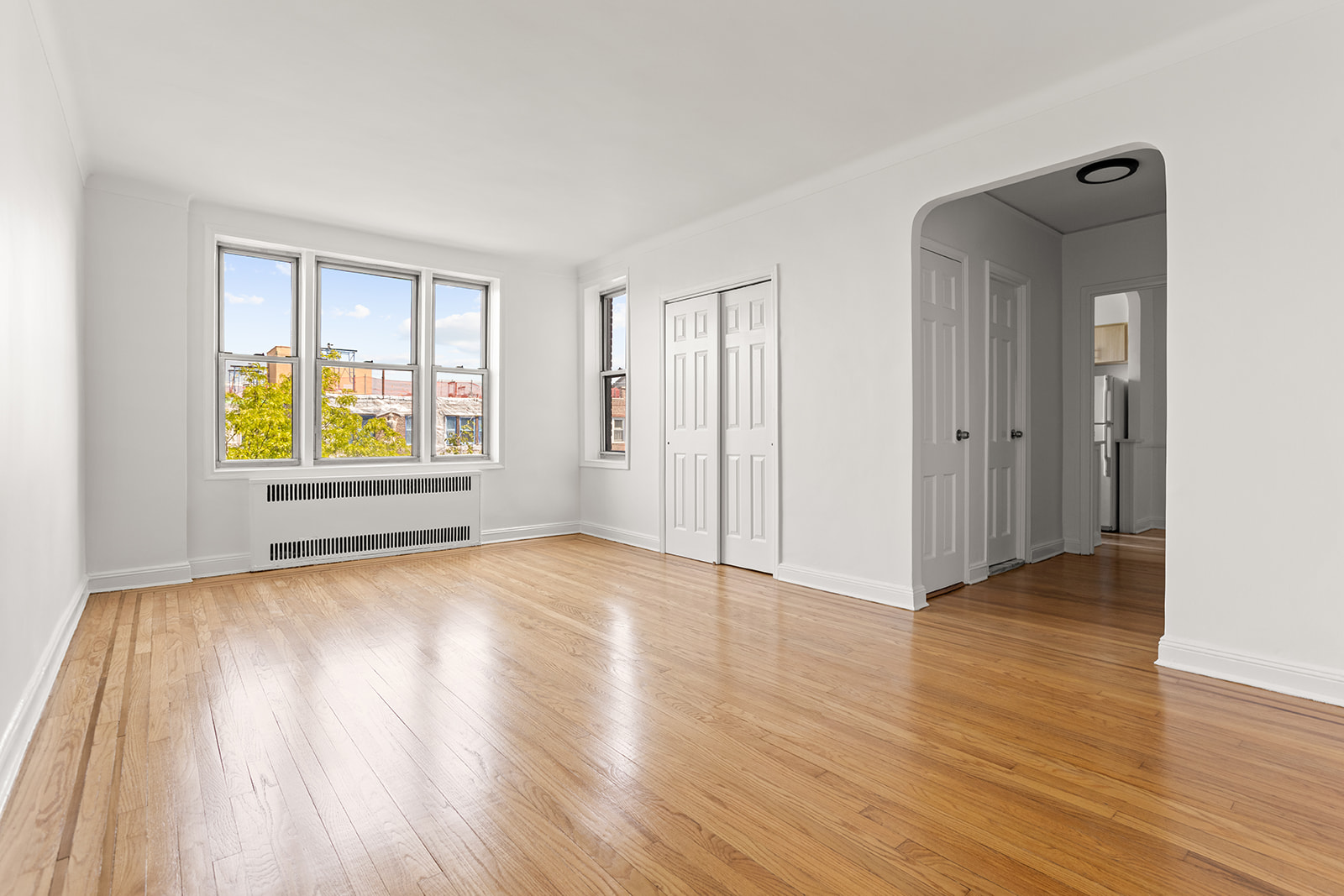 76-12 35th Avenue, Unit 6N Queens, NY 11372 - Photo 2 of 14 an empty room with wooden floor and windows