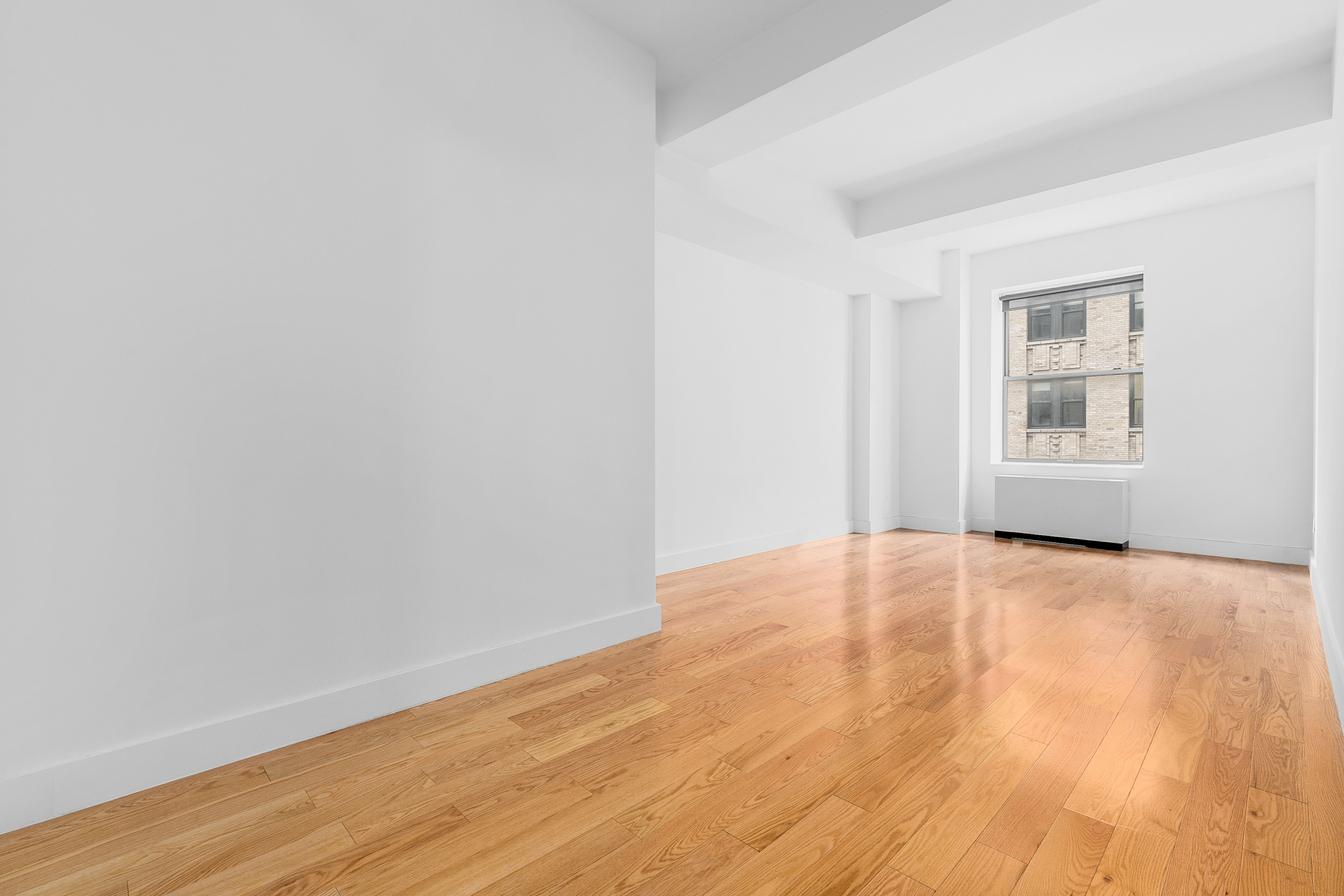 99 John Street, Unit 819 Manhattan, NY 10038 - Photo 2 of 20 a view of an empty room with wooden floor and a window