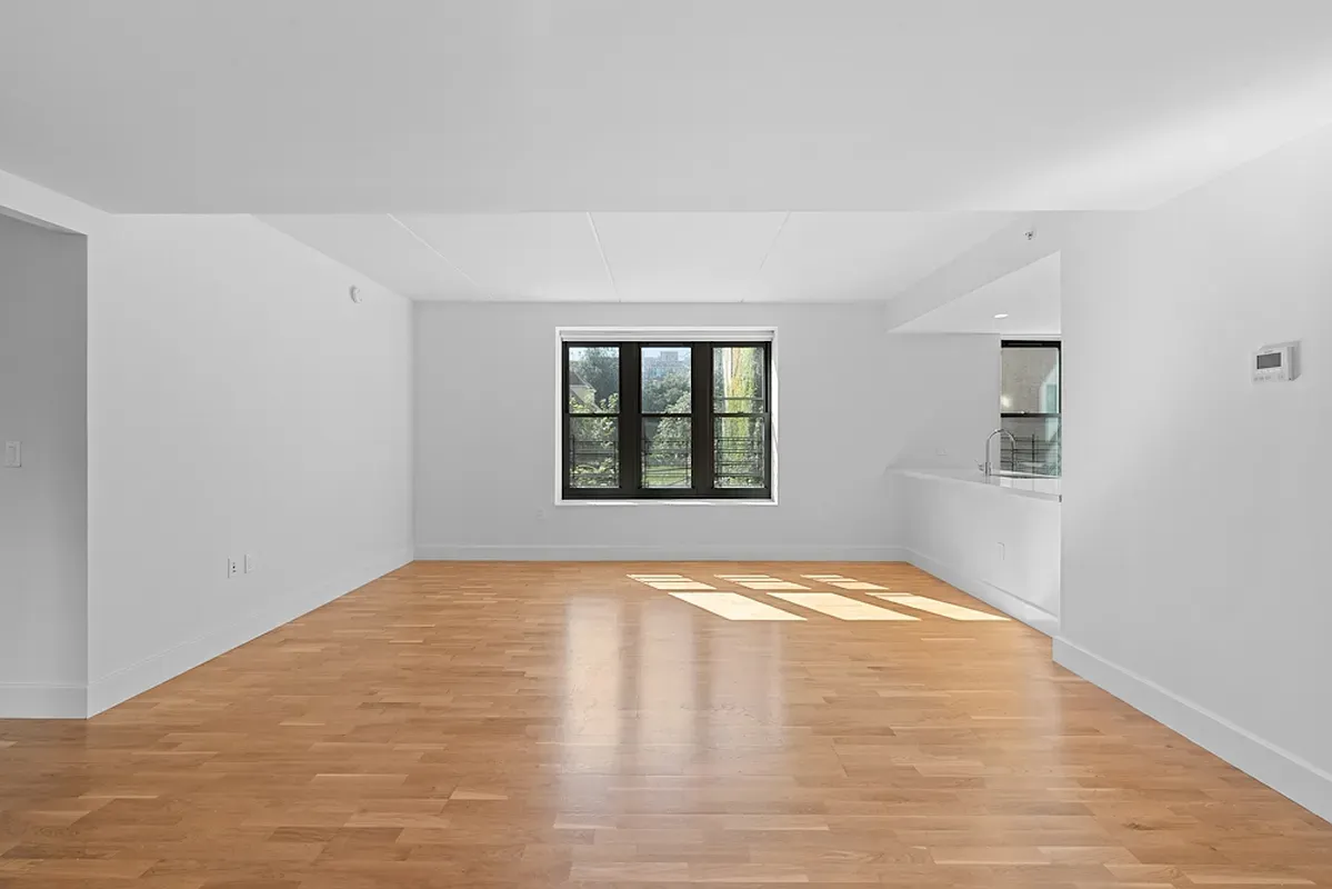 a view of an empty room with window and wooden floor