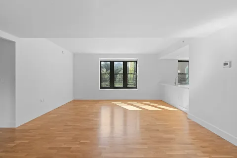 a view of an empty room with window and wooden floor