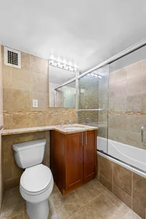 a bathroom with a granite countertop toilet a sink and mirror