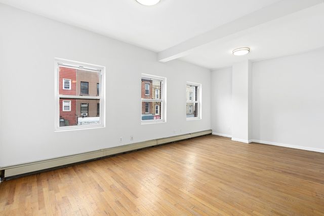 120 Smith Street, Unit 1 Brooklyn, NY 11201 - Photo 4 of 11 an empty room with wooden floor and windows