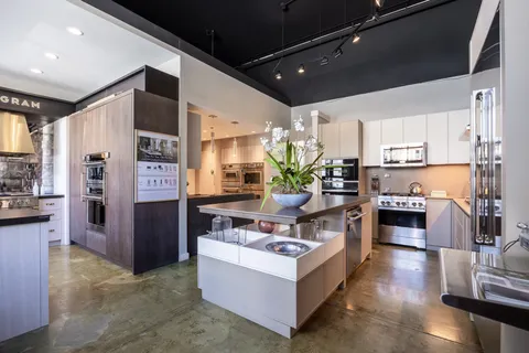 a living room with stainless steel appliances furniture a fireplace and a view of kitchen
