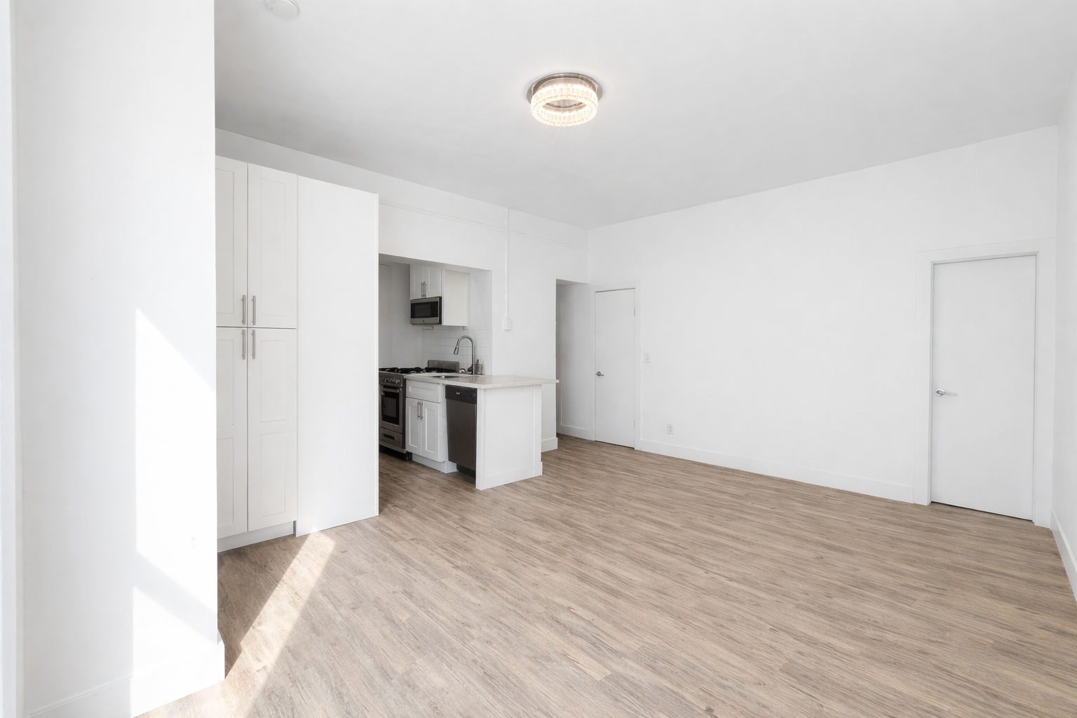 164 West 128th Street, Unit 3C Manhattan, NY 10027 - Photo 4 of 8 a view of empty room with wooden floor and kitchen