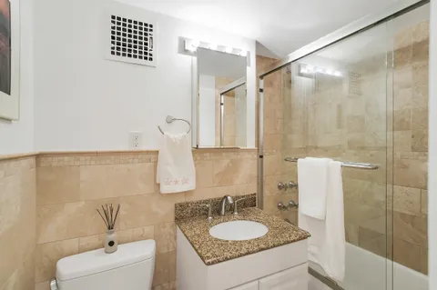 a bathroom with a granite countertop sink a mirror and shower