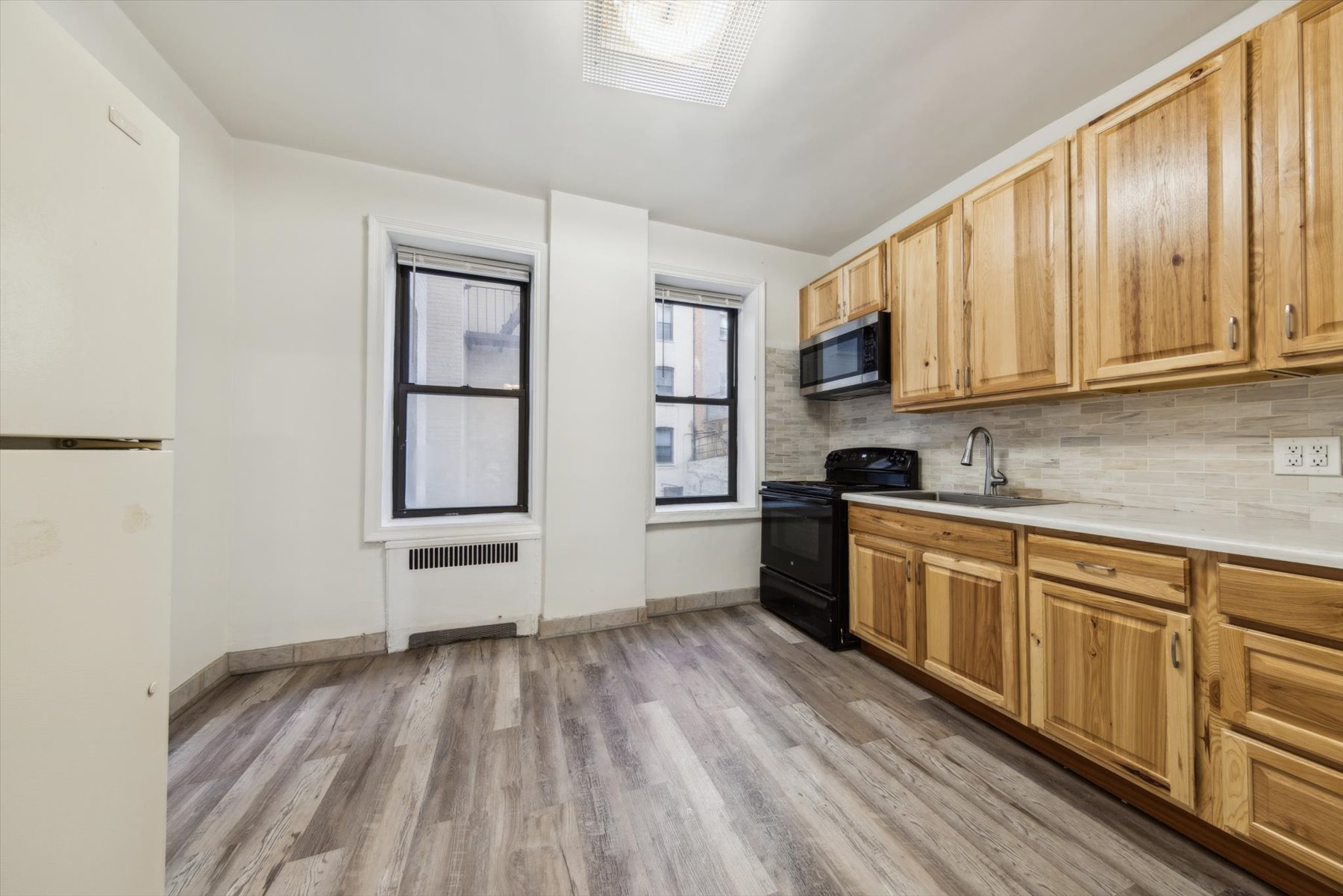 9701 Shore Road, Unit 1C Brooklyn, NY 11209 - Photo 6 of 8 a kitchen with granite countertop wooden floors and wide window
