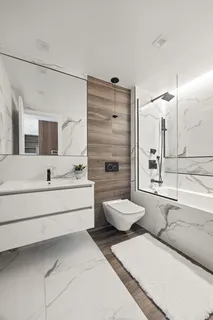 a bathroom with a double vanity sink a toilet a mirror and bathtub