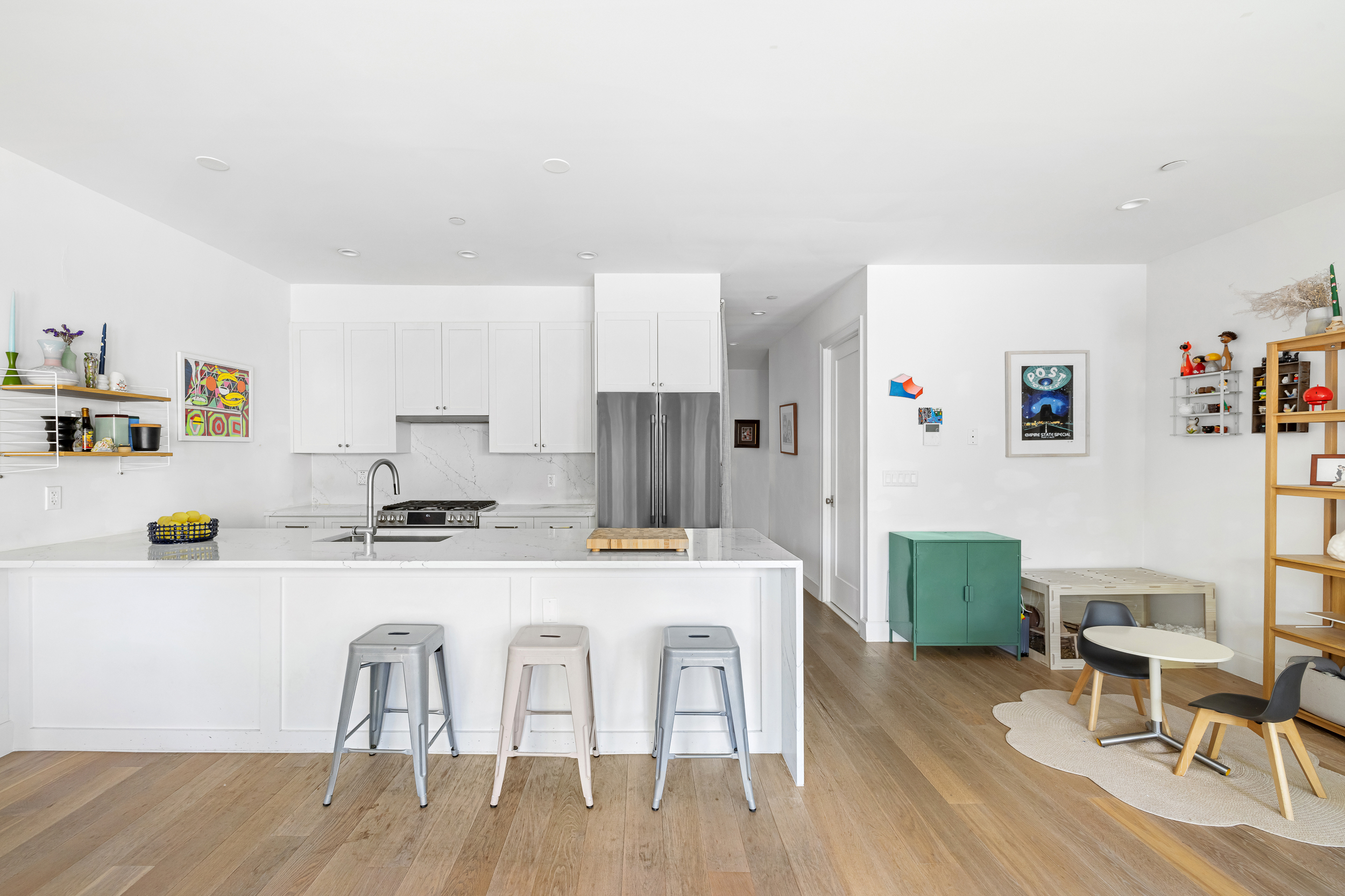 49 East 4th Street Brooklyn, NY 11218 - Photo 5 of 16 a kitchen with stainless steel appliances a table chairs refrigerator and wooden floor