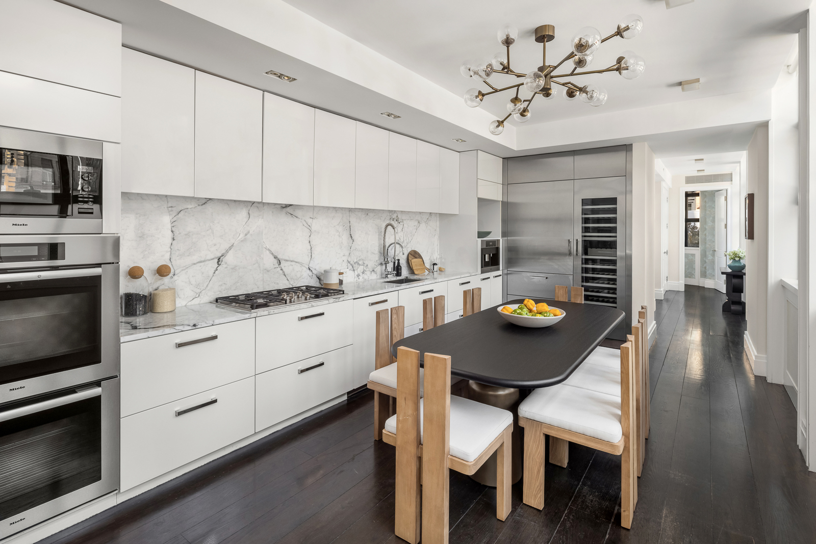 137 Franklin Street, Unit 1 Manhattan, NY 10013 - Photo 8 of 25 a kitchen with stainless steel appliances a white table chairs and a refrigerator