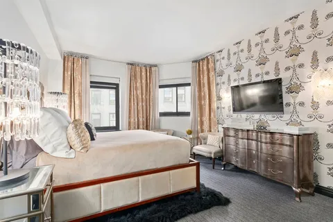 a bedroom with bed and flat tv screen on dresser