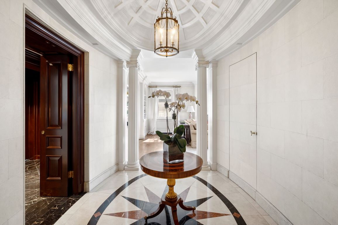 a view of a hallway with wooden floor and a chandelier