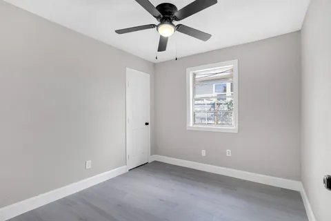 an empty room with a window and a ceiling fan