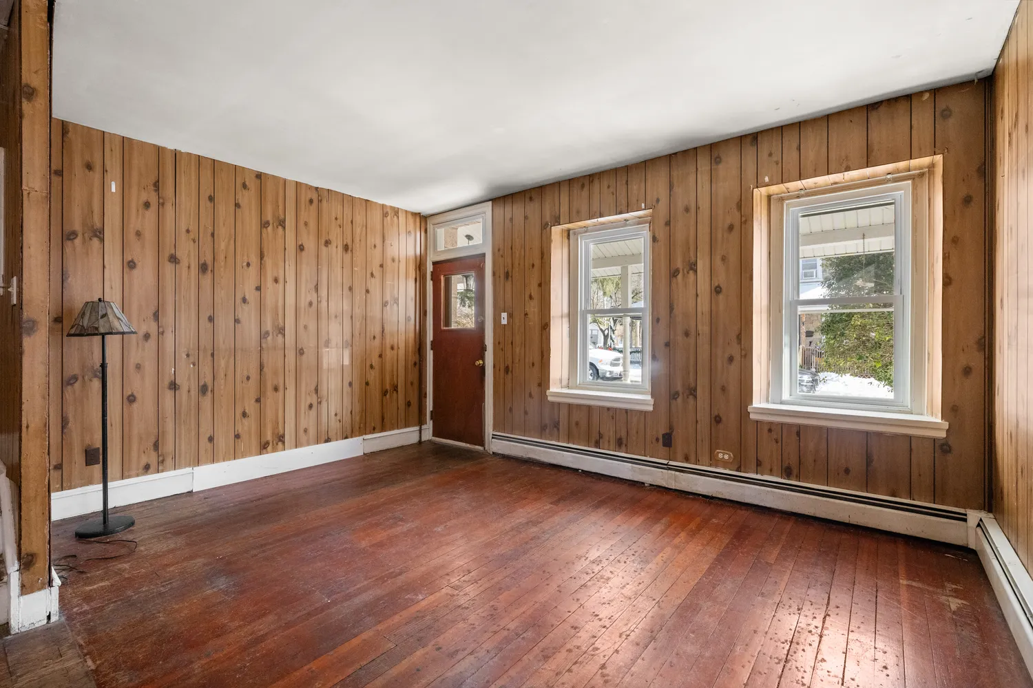 an empty room with wooden floor and windows