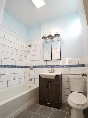 2446 Bedford Avenue, Unit 1 Brooklyn, NY 11226 - Photo 5 of 15 a bathroom with a sink toilet vanity and bathtub
