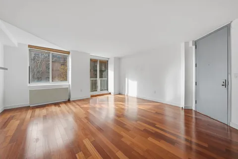 a view of an empty room with wooden floor and windows