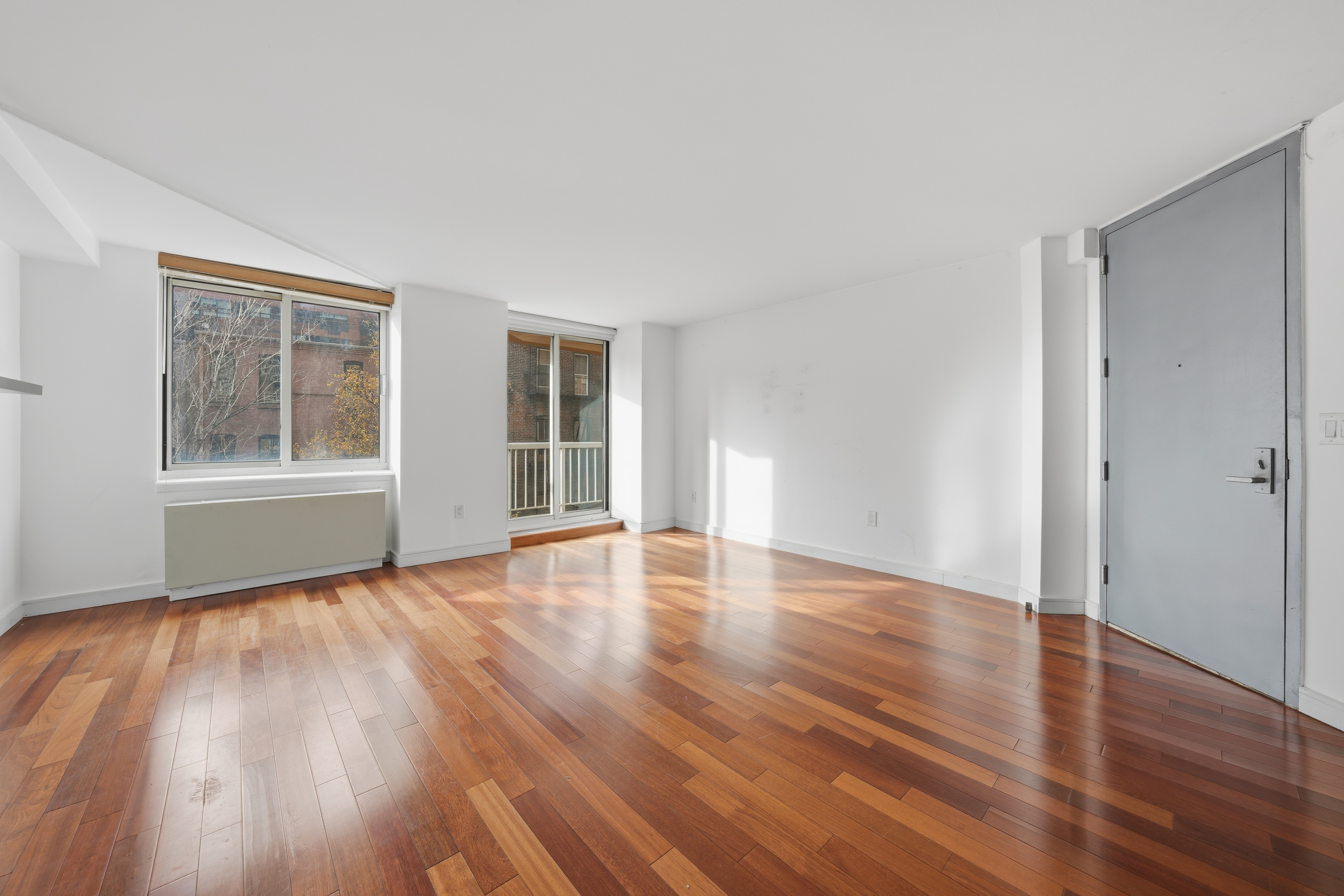206 East 95th Street, Unit 6B Manhattan, NY 10128 - Photo 6 of 25 a view of an empty room with wooden floor and windows