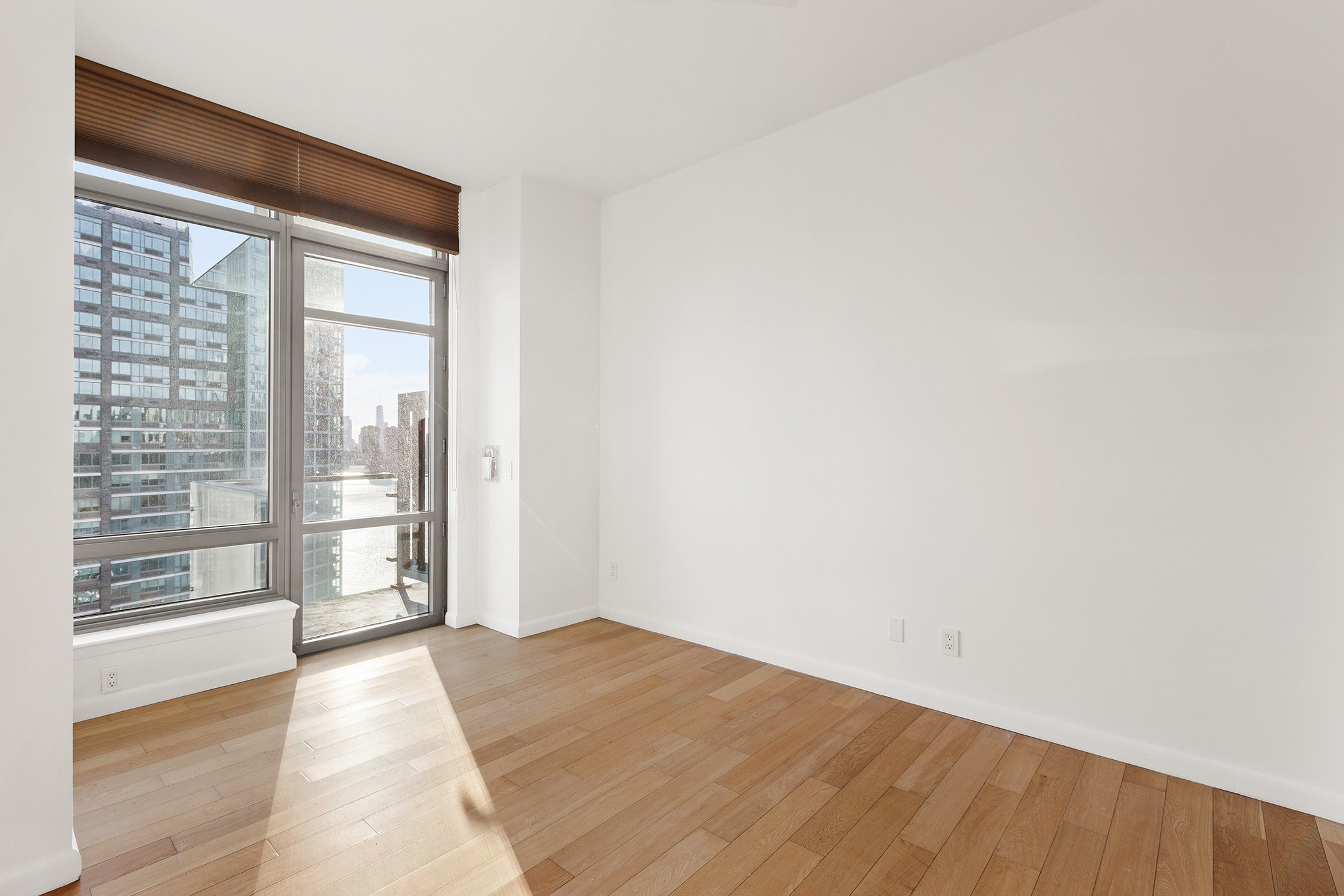 46-30 Center Boulevard, Unit PH8 Queens, NY 11109 - Photo 15 of 32 a view of an empty room with wooden floor and a window