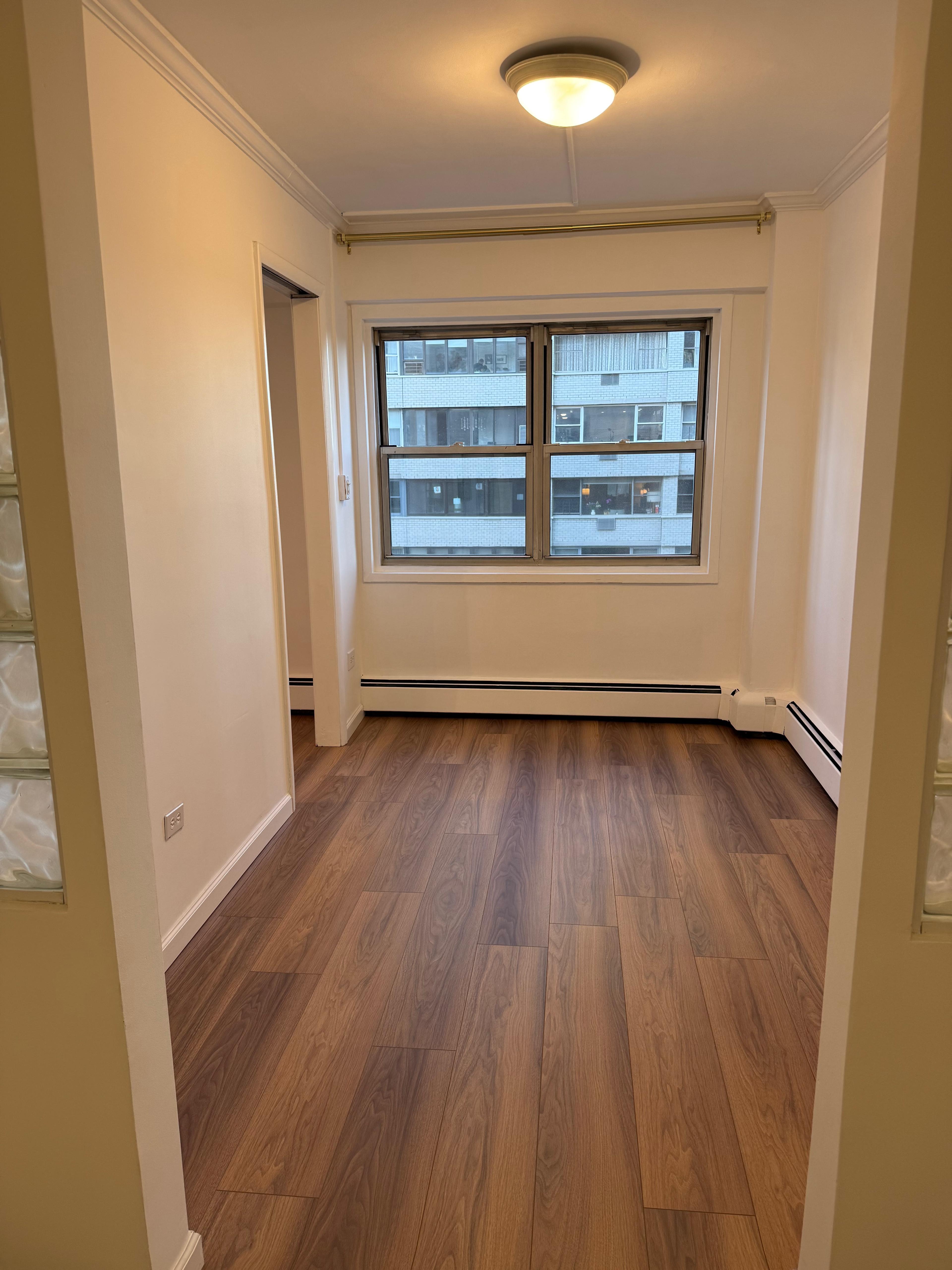 40 Sutton Place, Unit 7A Manhattan, NY 10022 - Photo 3 of 11 an empty room with wooden floor and windows