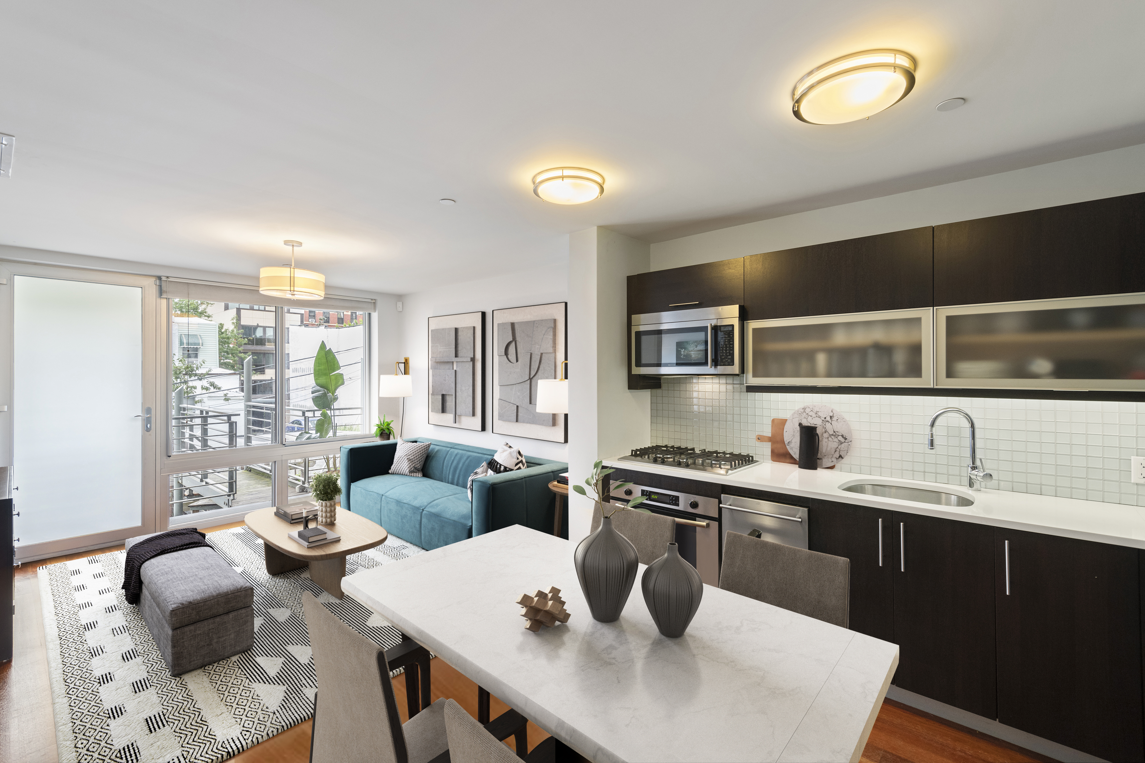 a living room with stainless steel appliances granite countertop a sink a stove a dining table and chairs with wooden floor