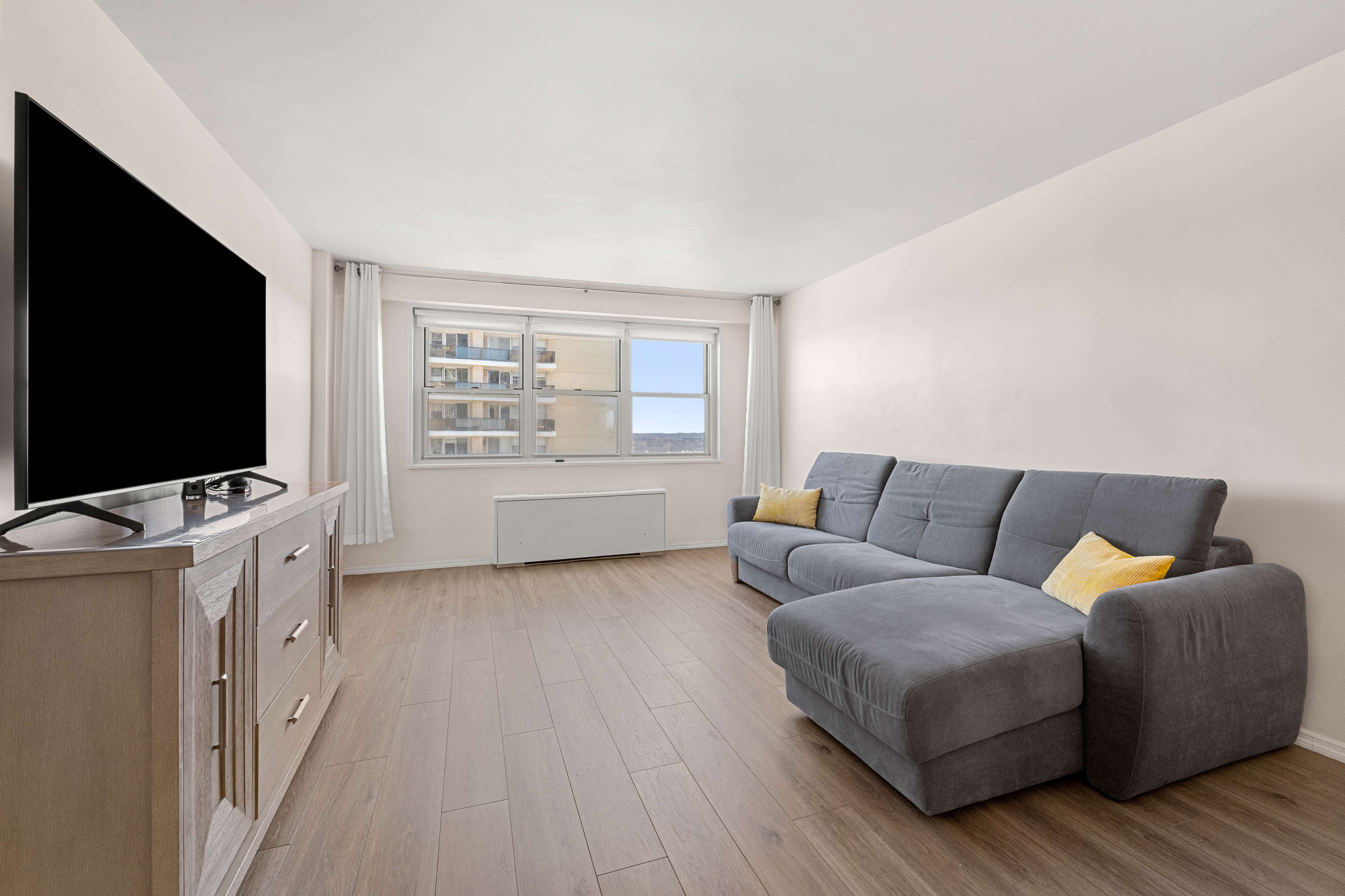 102-10 66th Road, Unit 21K Queens, NY 11375 - Photo 2 of 16 a living room with furniture and a flat screen tv