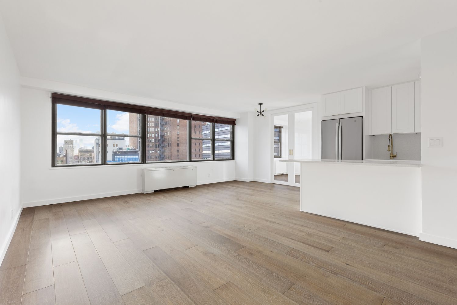 a view of an empty room with a window and wooden floor