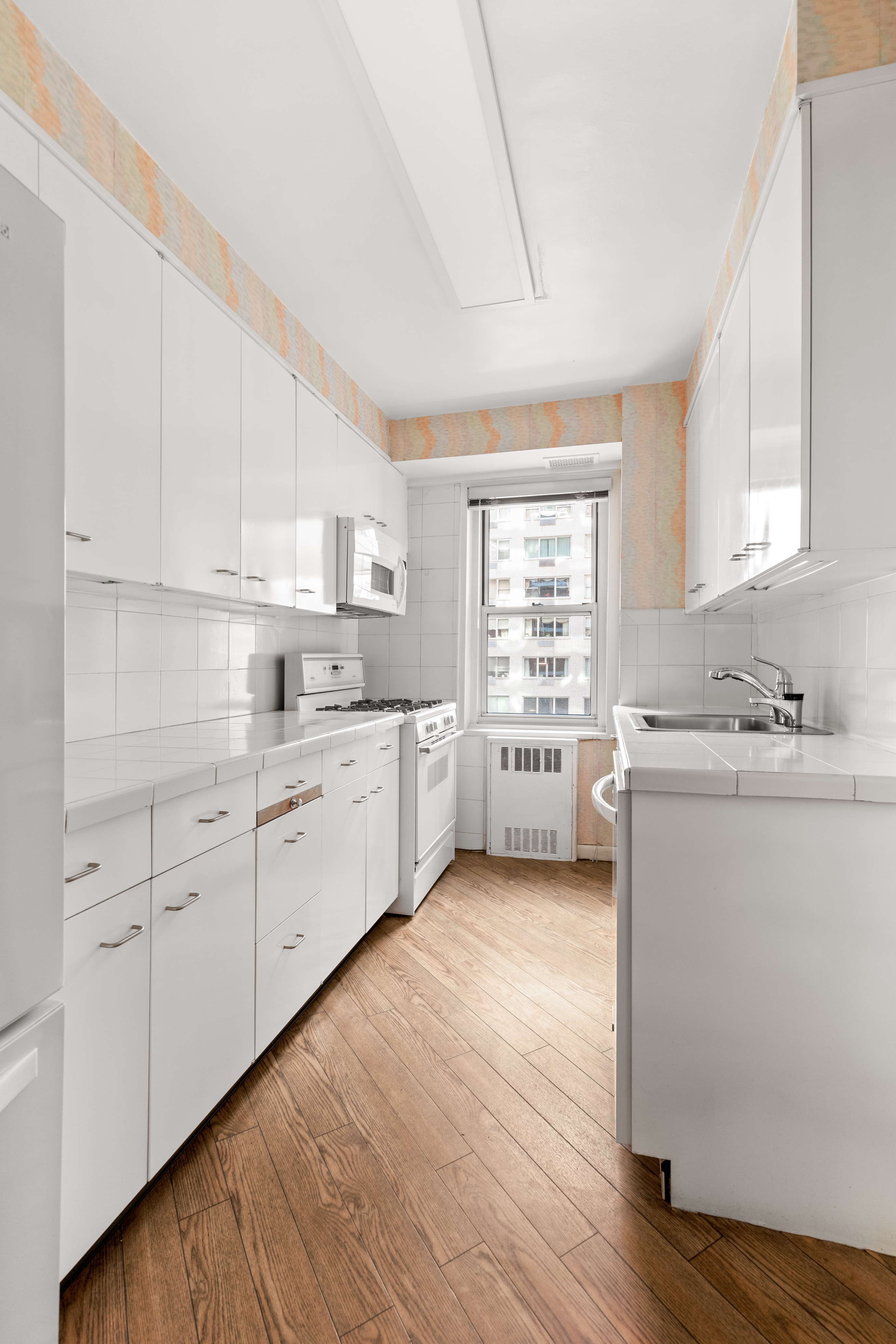 50 Sutton Place South, Unit 7A Manhattan, NY 10022 - Photo 8 of 16 a kitchen with cabinets wooden floor and a window