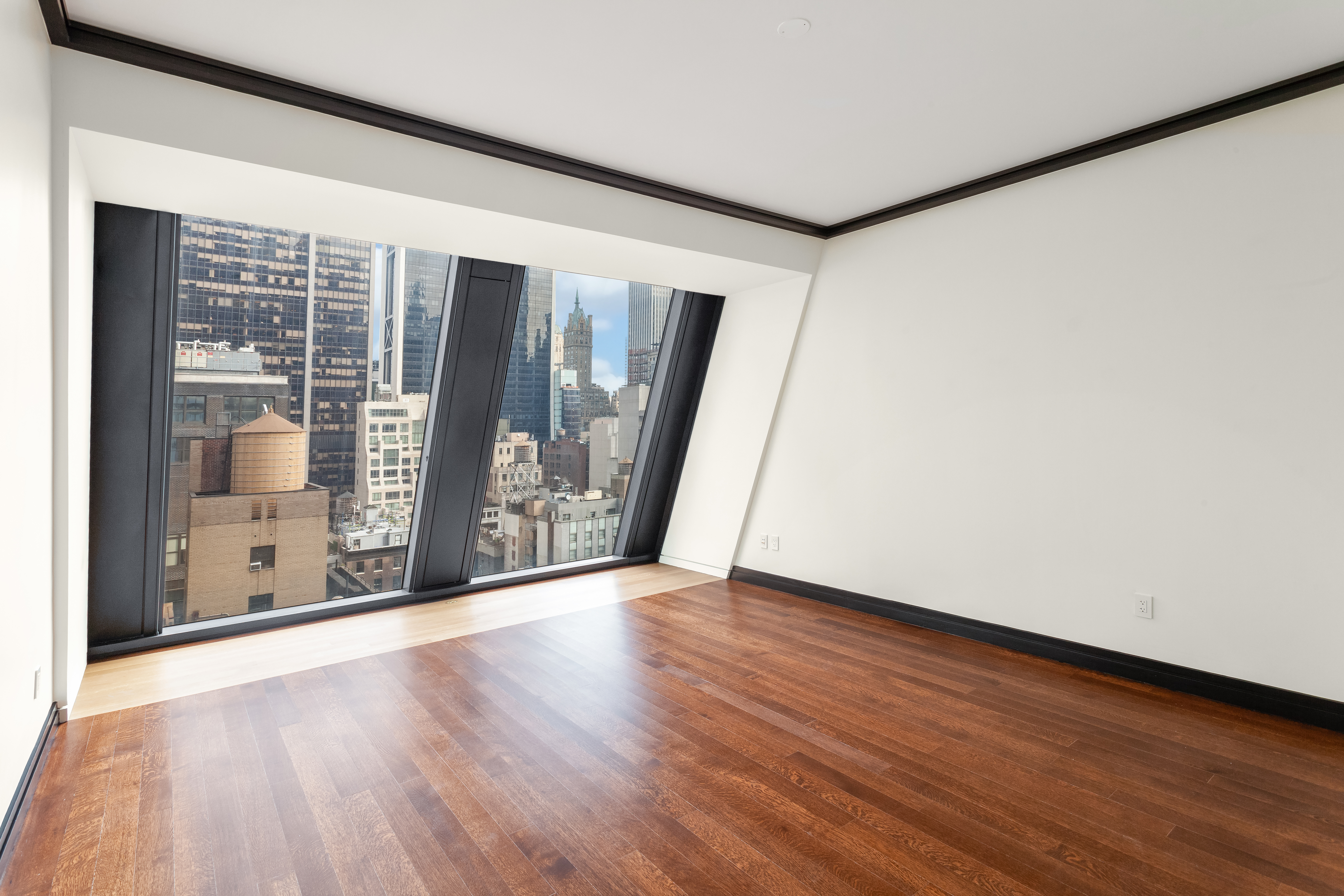53 West 53rd Street, Unit 16C Manhattan, NY 10019 - Photo 1 of 12 a view of an empty room with wooden floor and a window