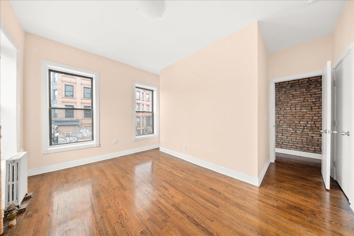 478 Halsey Street, Unit 1 Brooklyn, NY 11233 - Photo 6 of 10 an empty room with wooden floor and windows