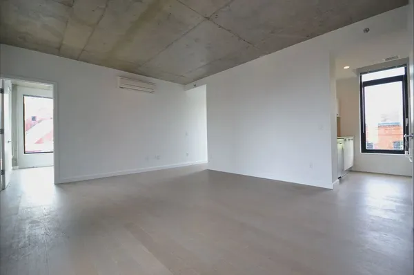 a view of an empty room with a window and wooden floor