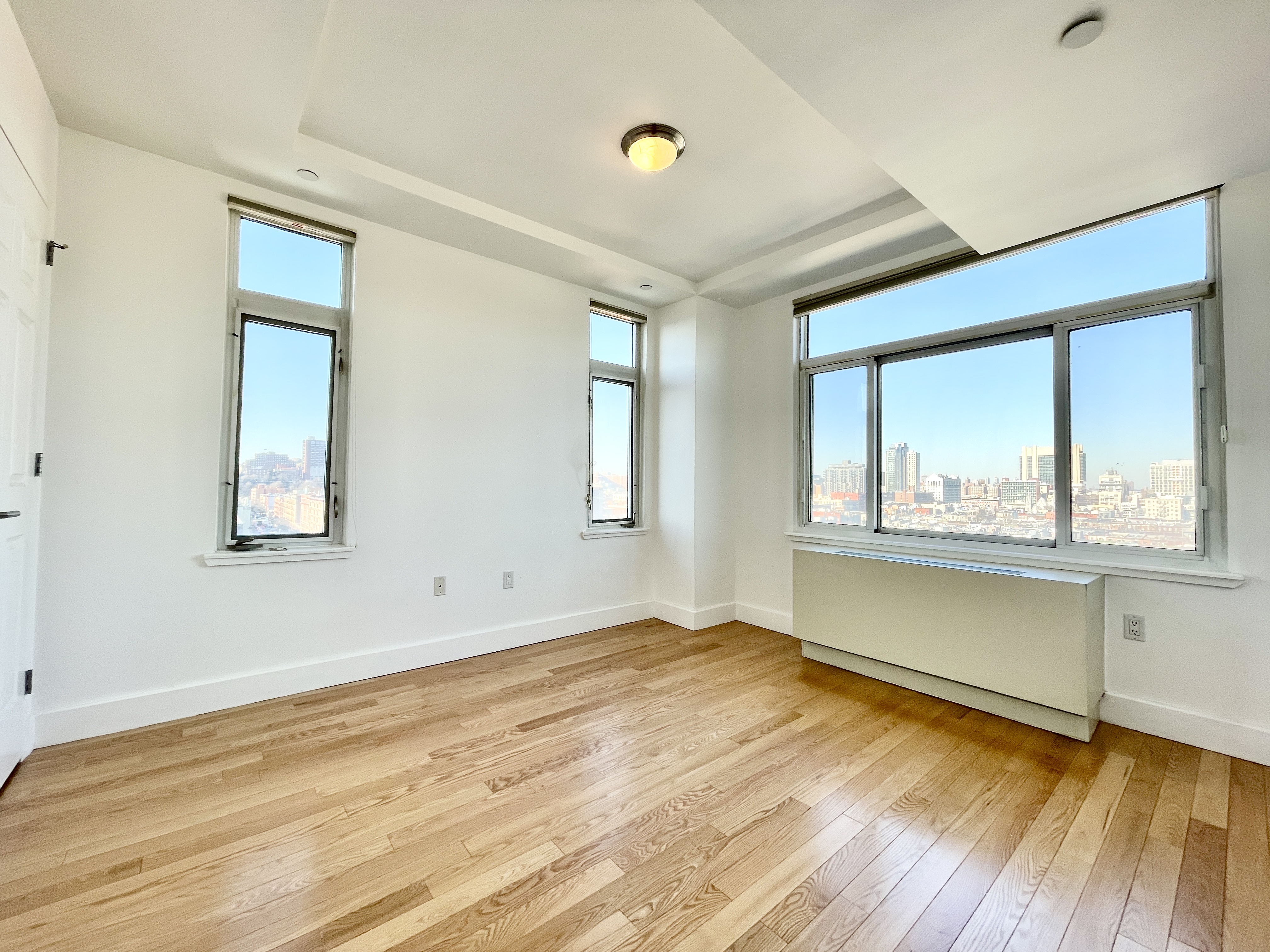 106 West 116th Street, Unit 12A Manhattan, NY 10026 - Photo 5 of 13 a view of an empty room with wooden floor and a window