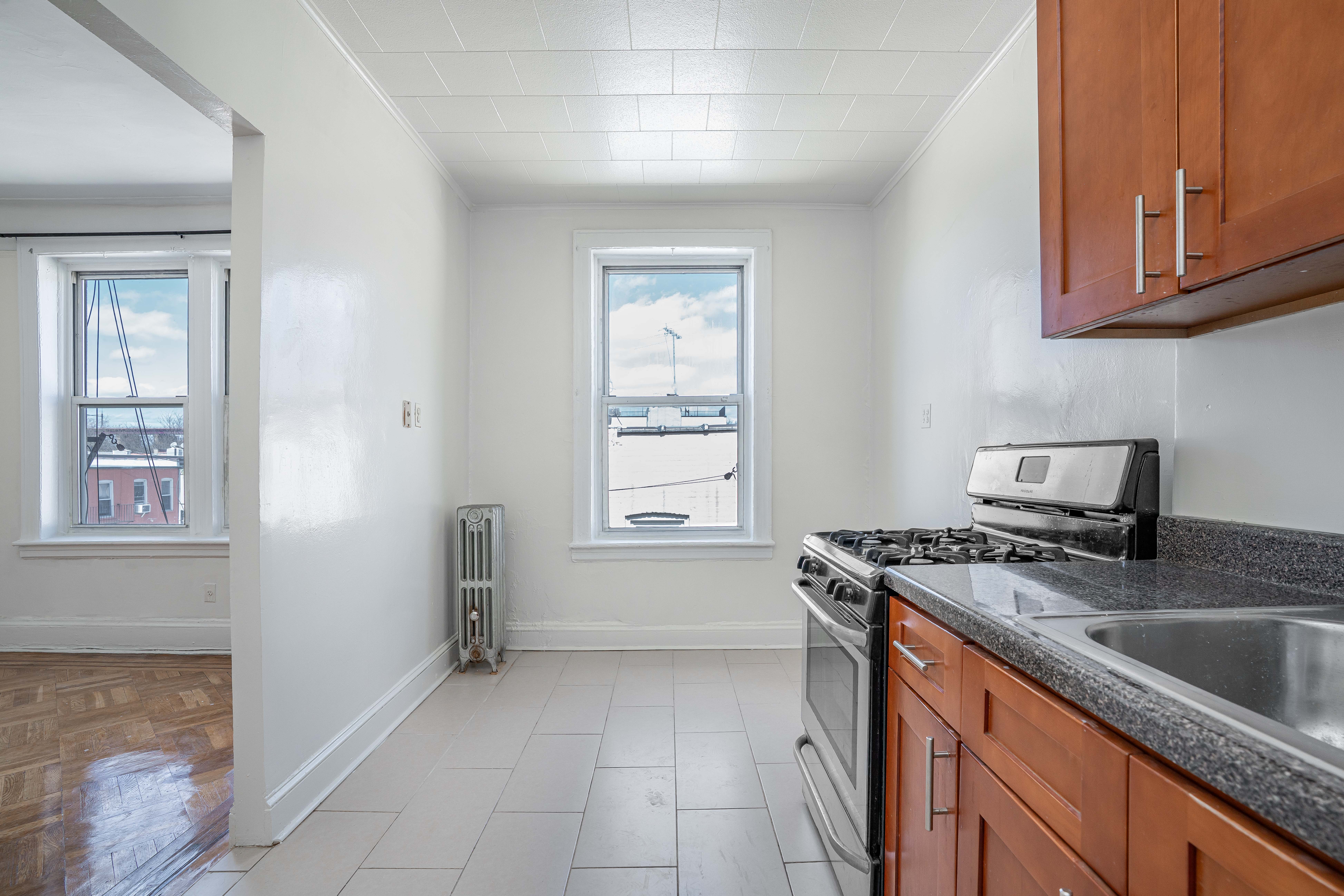 27-15 24th Avenue, Unit 2 Queens, NY 11105 - Photo 2 of 10 a kitchen with stainless steel appliances granite countertop a sink stove and cabinets
