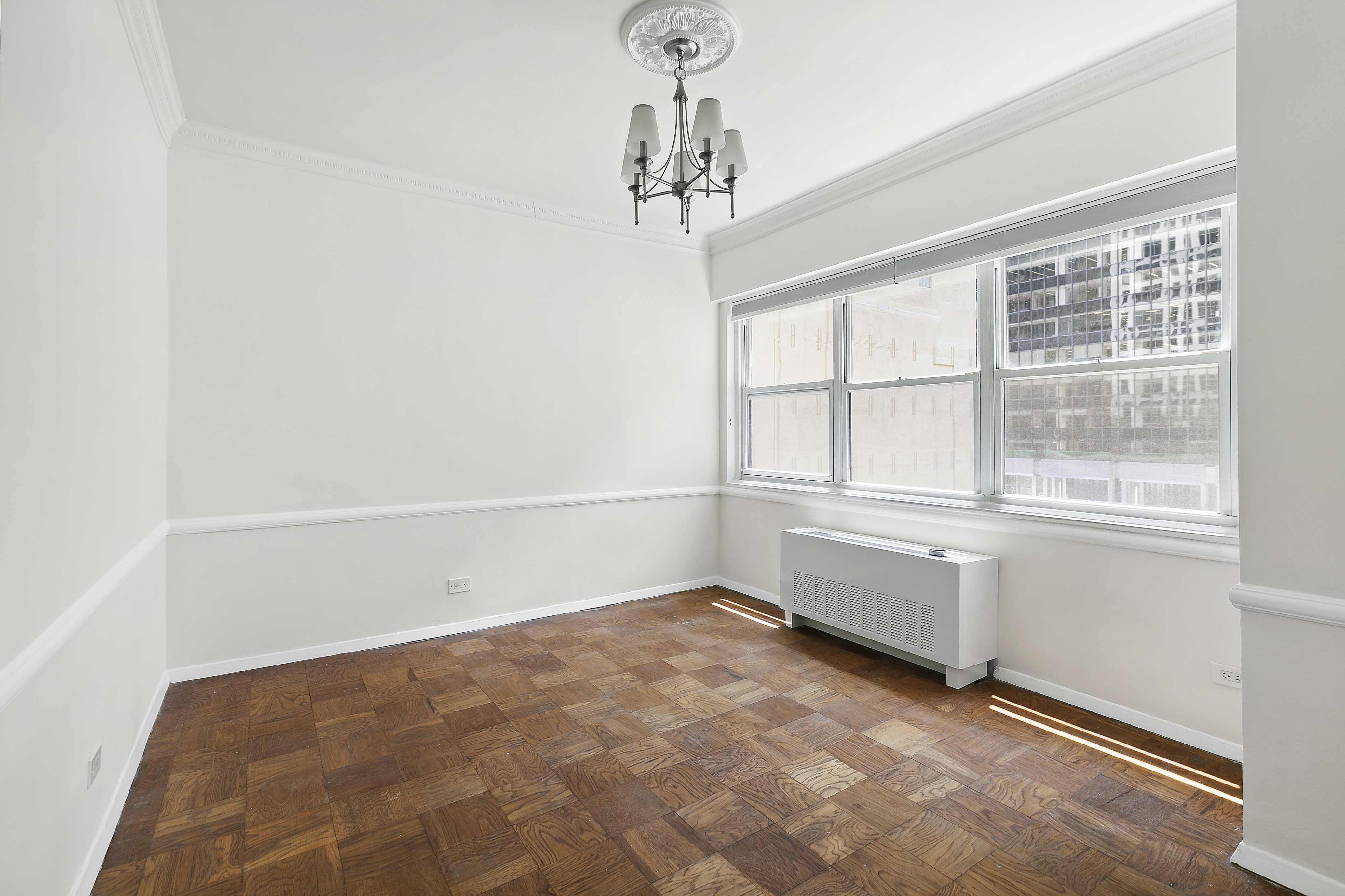 58 West 58th Street, Unit 4C Manhattan, NY 10019 - Photo 10 of 14 an empty room with a windows and chandelier