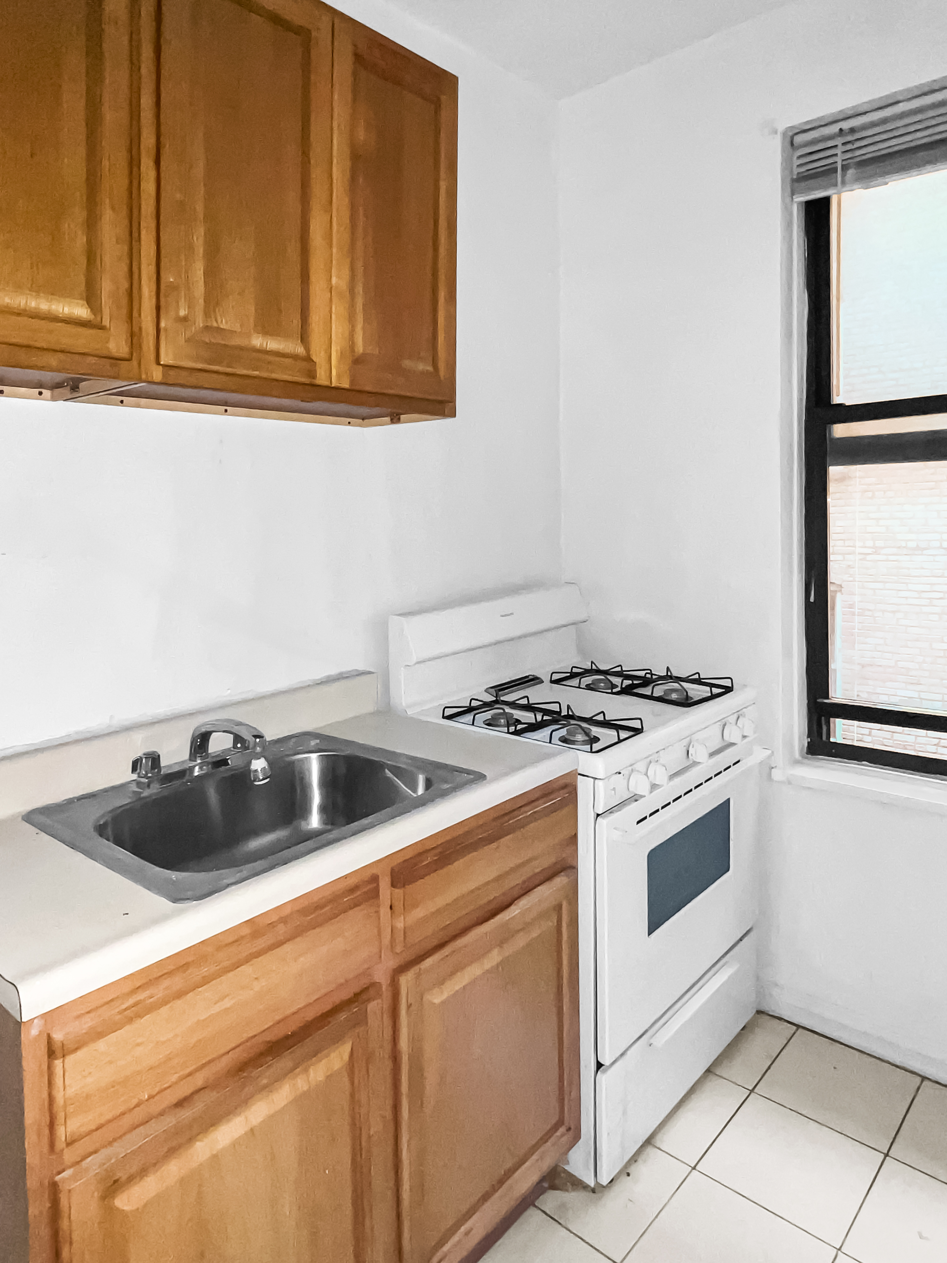 2776 Jerome Avenue, Unit 3C Bronx, NY 10468 - Photo 5 of 8 a kitchen with white cabinets and white appliances