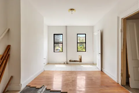 a view of an empty room with window and wooden floor