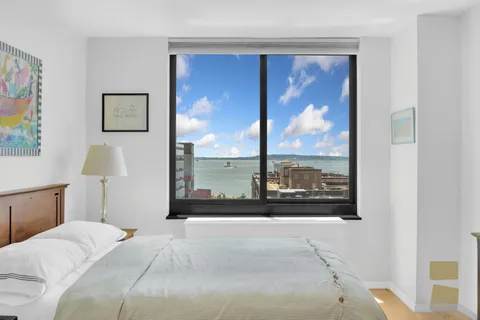 a bedroom with a bed and a large window with the outer view