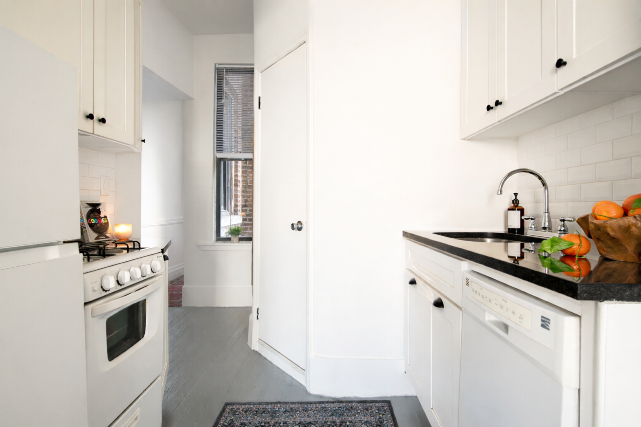 264 West 22nd Street Manhattan, NY 10011 - Photo 4 of 7 a kitchen with a sink stove and white cabinets