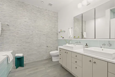 a bathroom with a double vanity sink a mirror and a toilet