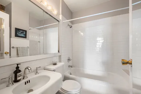 a bathroom with a bathtub shower sink vanity and toilet