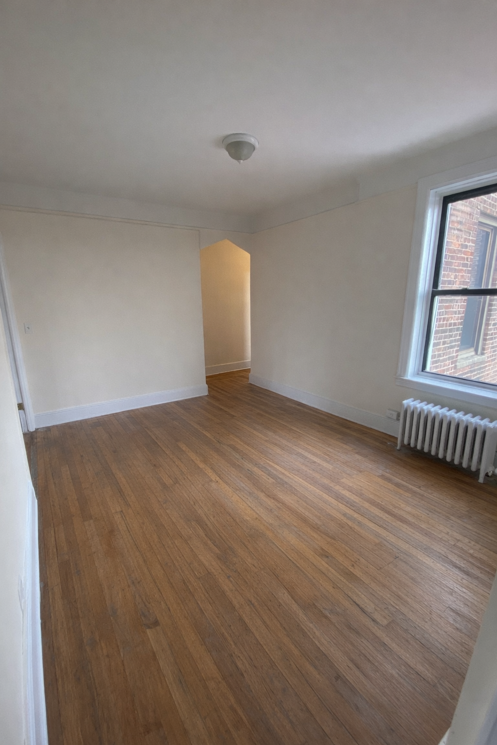 28-23 42nd Street, Unit D5 Queens, NY 11103 - Photo 5 of 10 an empty room with wooden floor and windows