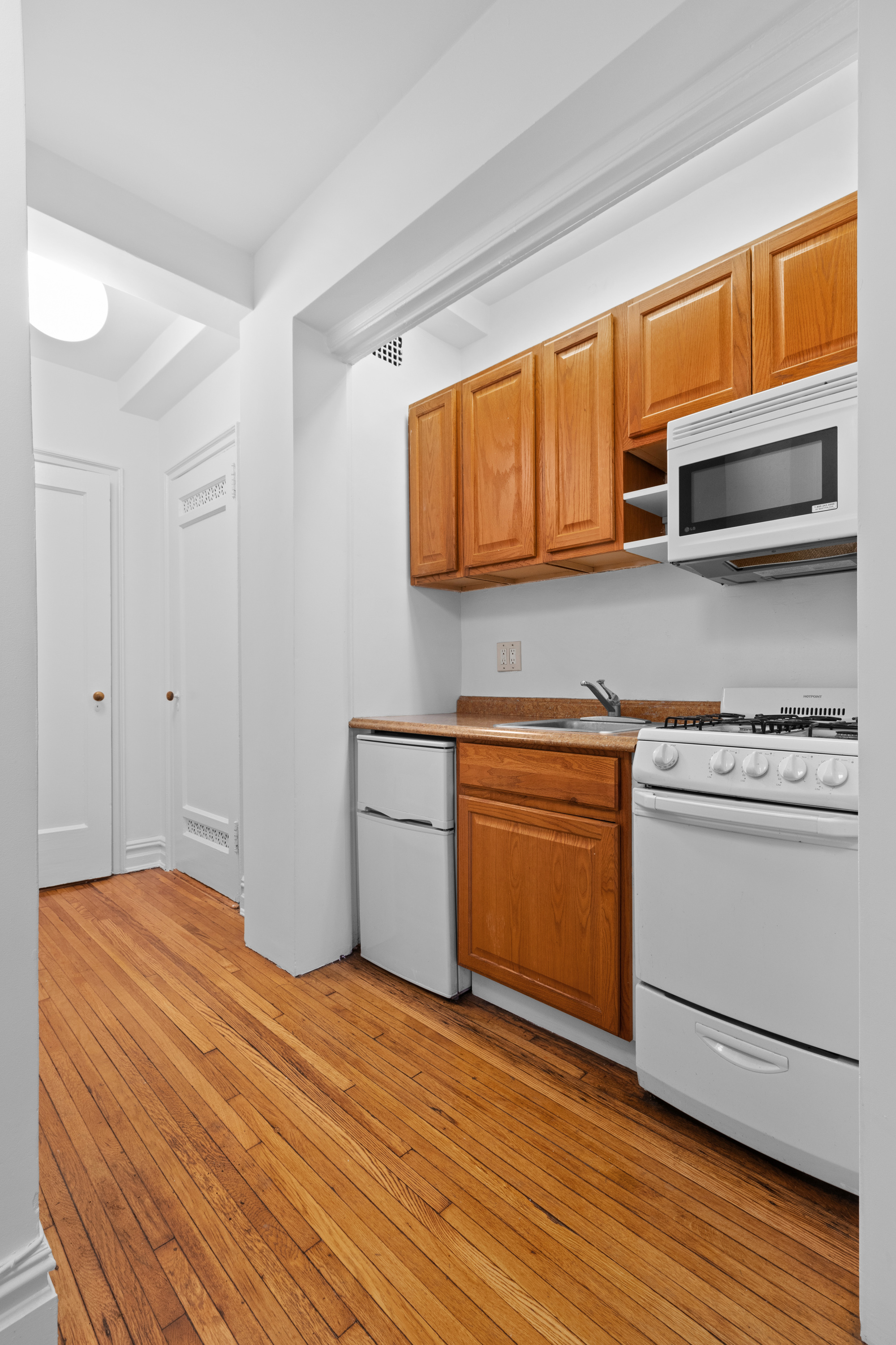 457 West 57th Street, Unit 304 Manhattan, NY 10019 - Photo 4 of 7 a kitchen with stainless steel appliances granite countertop a sink and cabinets with wooden floor