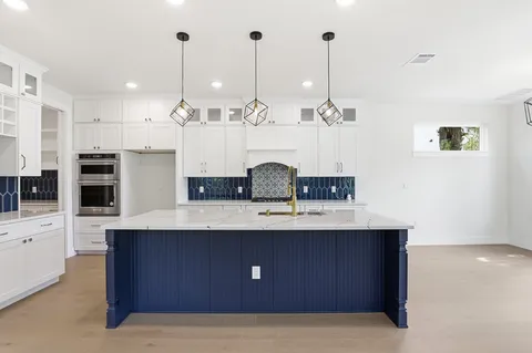 a kitchen with stainless steel appliances granite countertop a sink a oven a stove and a wooden floors