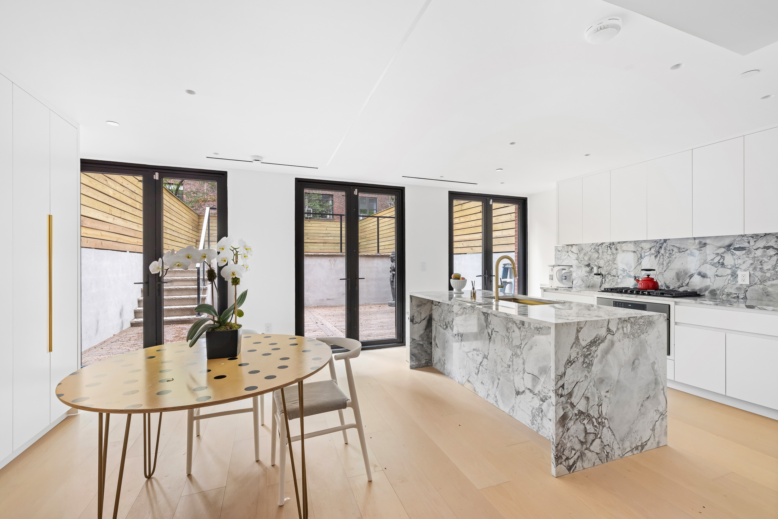 442 West 22nd Street Manhattan, NY 10011 - Photo 4 of 17 a kitchen with stainless steel appliances kitchen island granite countertop a refrigerator a stove top oven a dining table and chairs with wooden floor