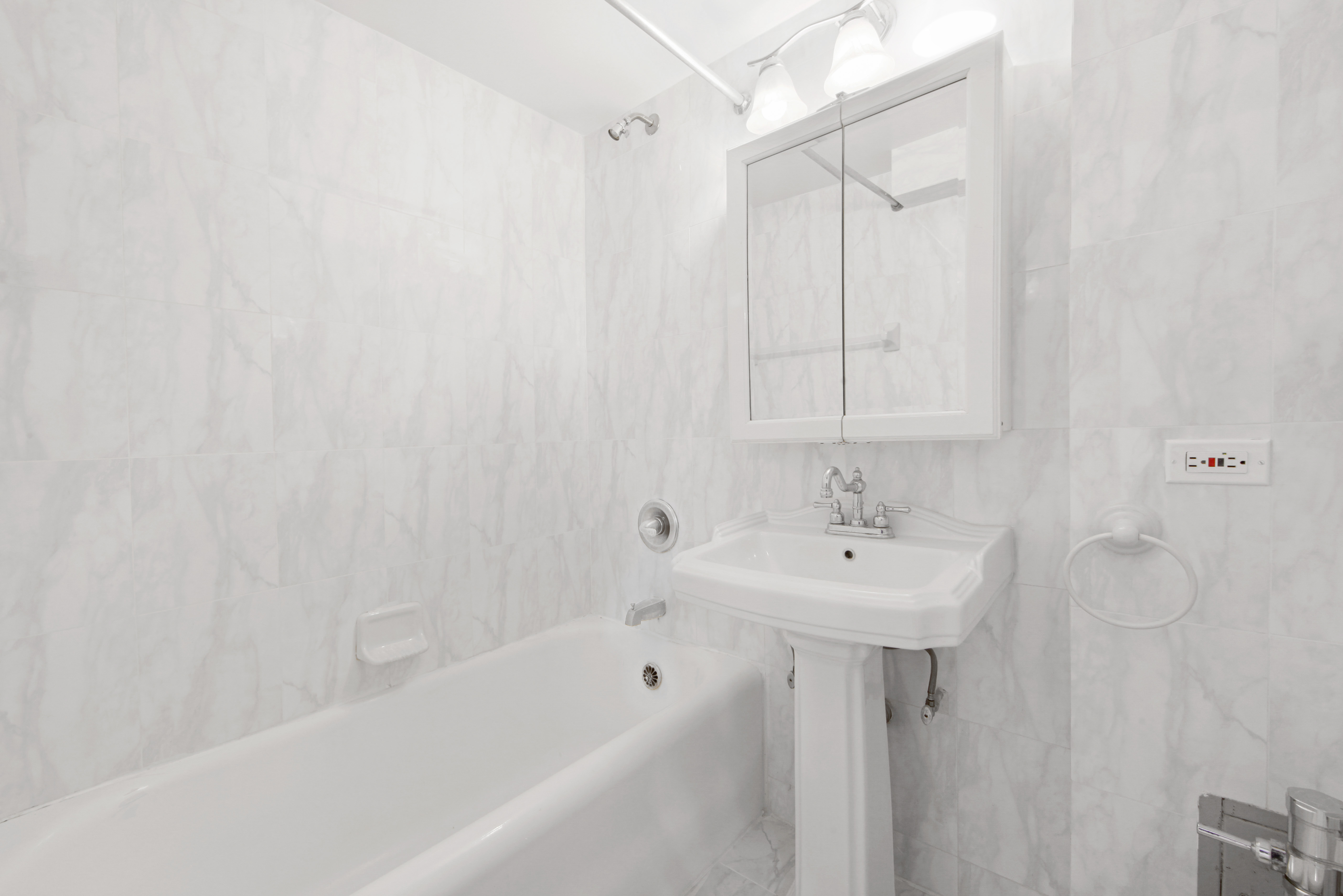 25 Tudor City Place, Unit 508 Manhattan, NY 10017 - Photo 7 of 17 a bathroom with a sink a mirror and a bathtub