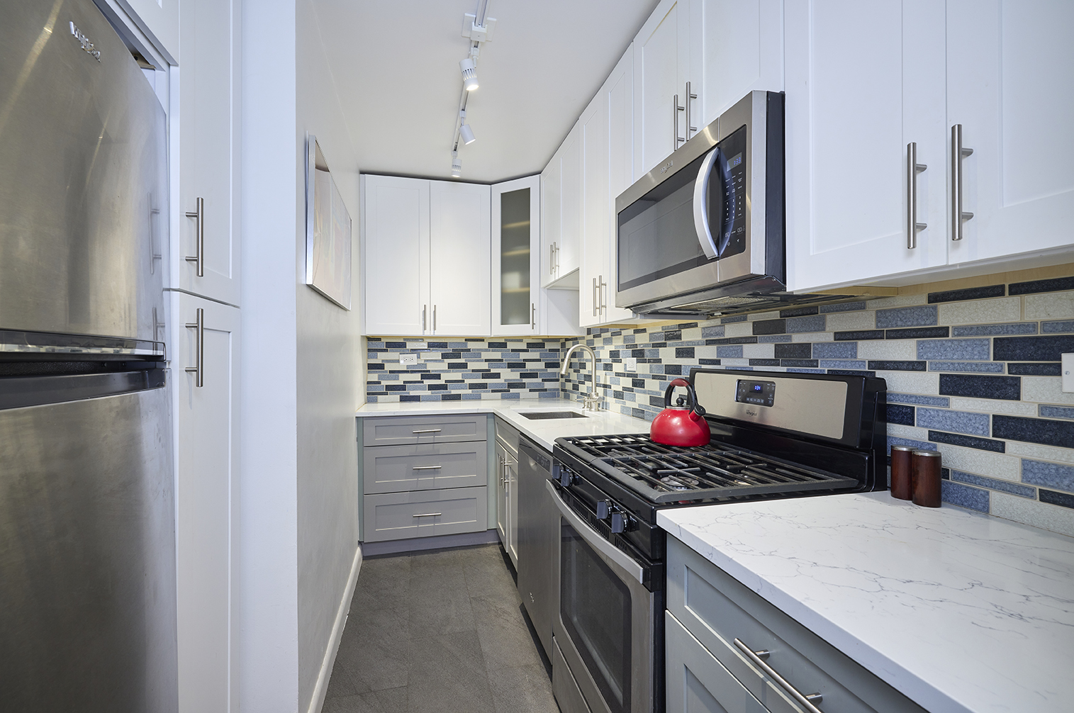 201 East 83rd Street, Unit 14E Manhattan, NY 10028 - Photo 4 of 8 a kitchen with stainless steel appliances granite countertop a stove and a microwave